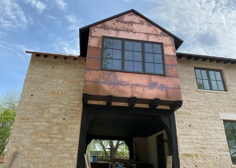 Copper metal panel facade on a stone building for Roof Repair in Greendale