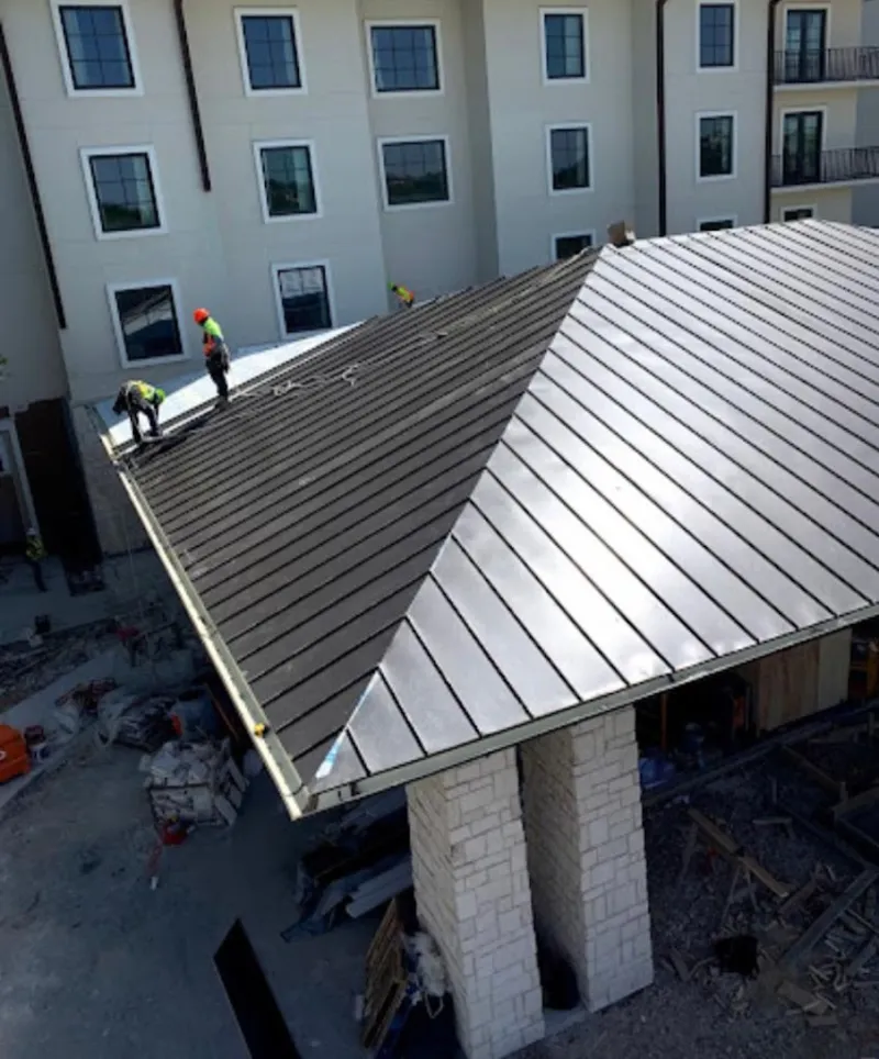 Crew installing standing seam metal roof panels on a commercial project in Greendale